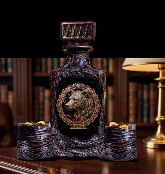 Personalized Bear Whiskey decanter glasses A dark textured glass bottle with a carved bear emblem and gold-toned lettering, displayed on a wooden table with two matching textured cups in a library setting.