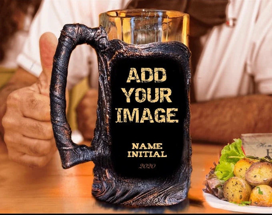A black beer mug with a personalized message that reads 'Add Your Image' and a name initial, with a background suggesting a casual dining setting.
